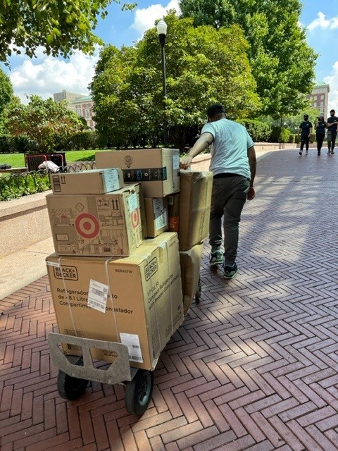 A cart of packages is transported to a residence hall.