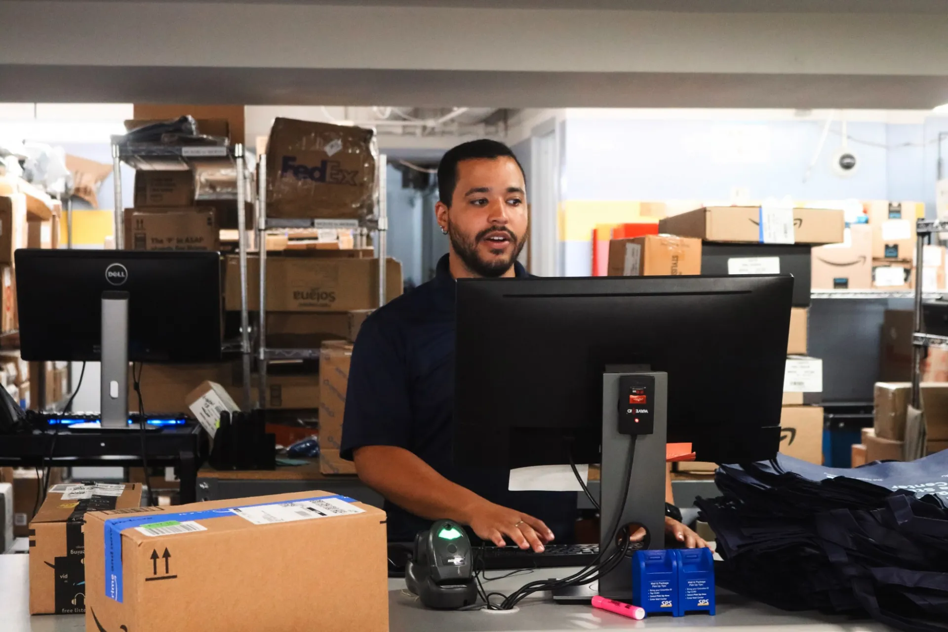 Mail center employee using the computer to find packages for a recipient