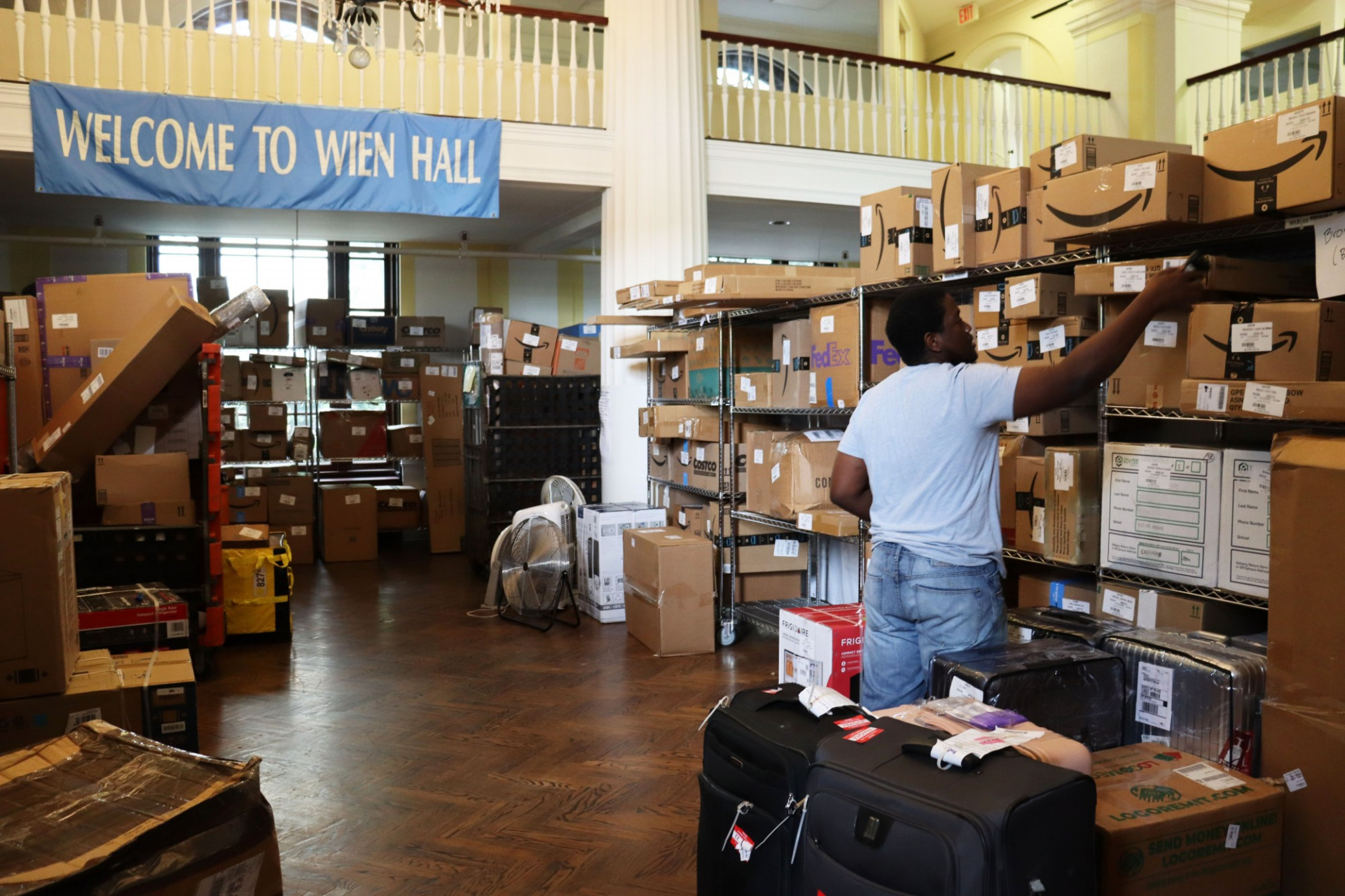Mail employee sorting packages on shelves in Wien Hall lounge