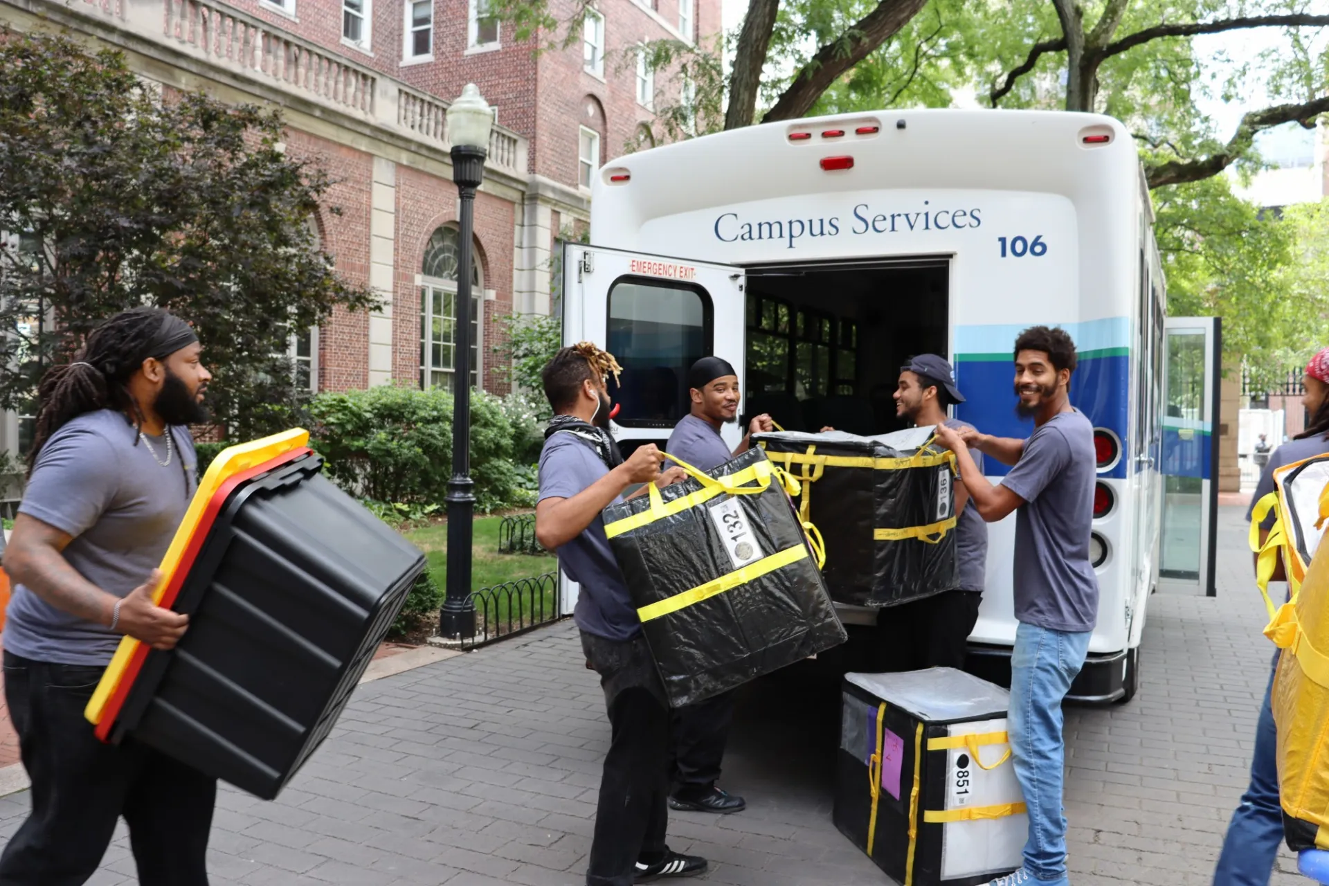 Mail team loading a bus with totes of packages to be delivered to residence halls